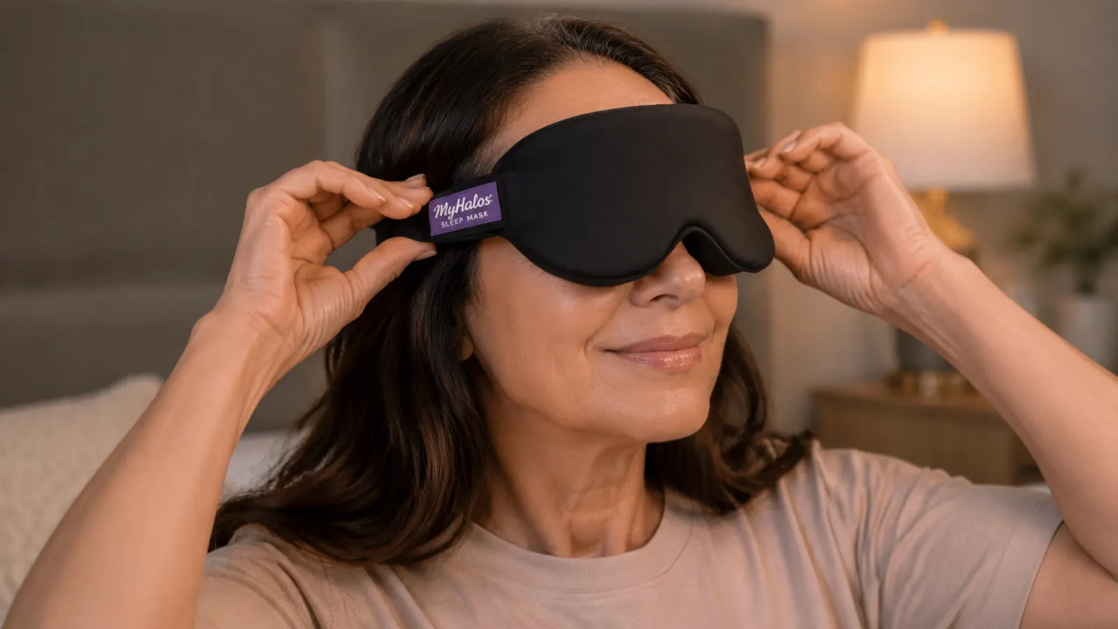 Close-up of hands adjusting the elastic strap of a MyHalos 3D sleep mask before putting it on