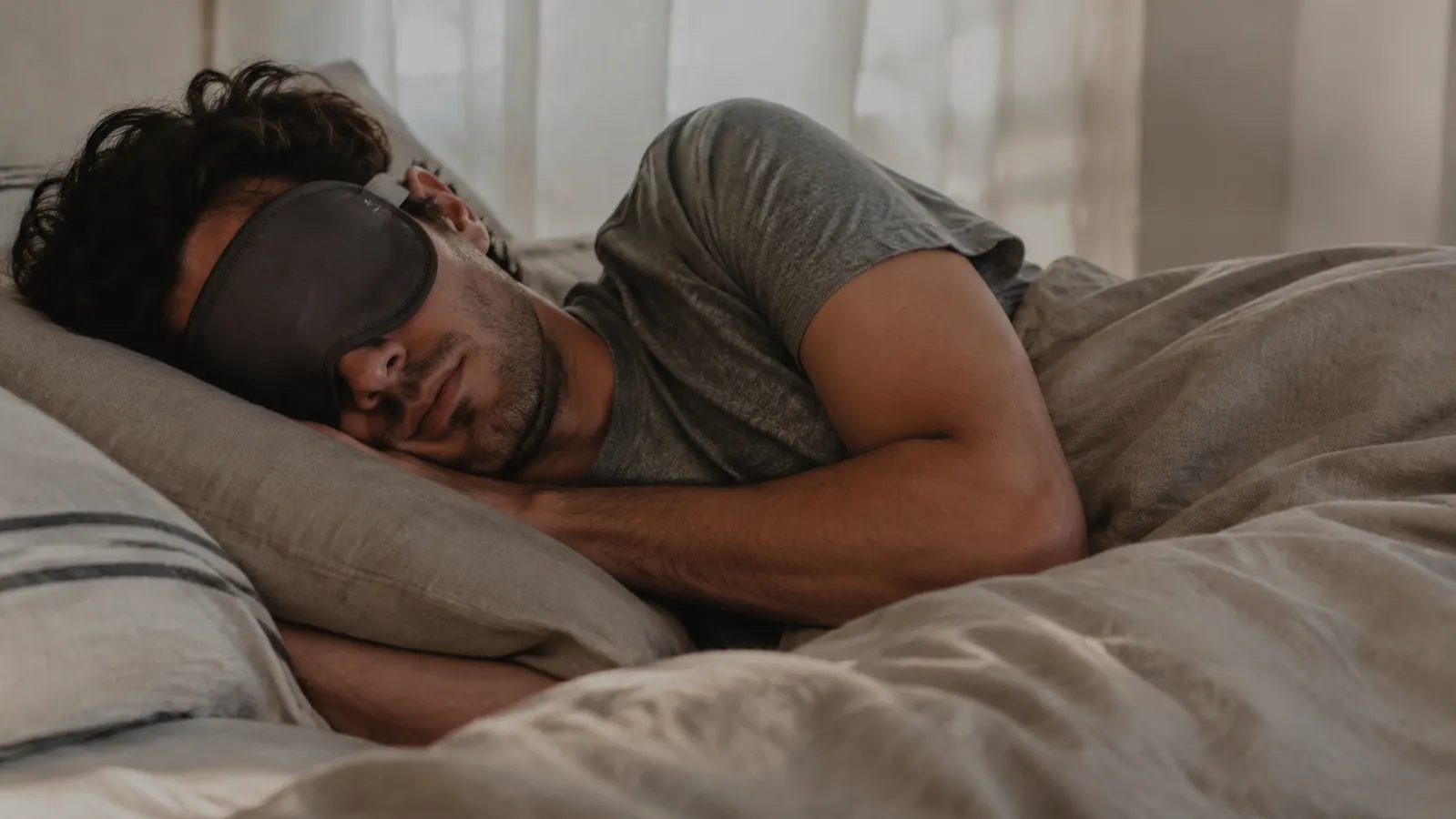 Person sleeping on their side with a contoured 3D sleep mask, soft morning light in the background